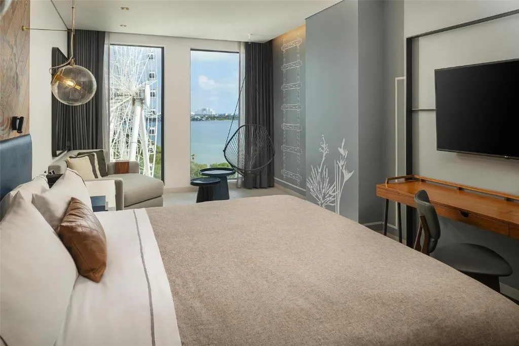 Habitación moderna en Canopy by Hilton Cancún con cama king, área de descanso y vista a la laguna.