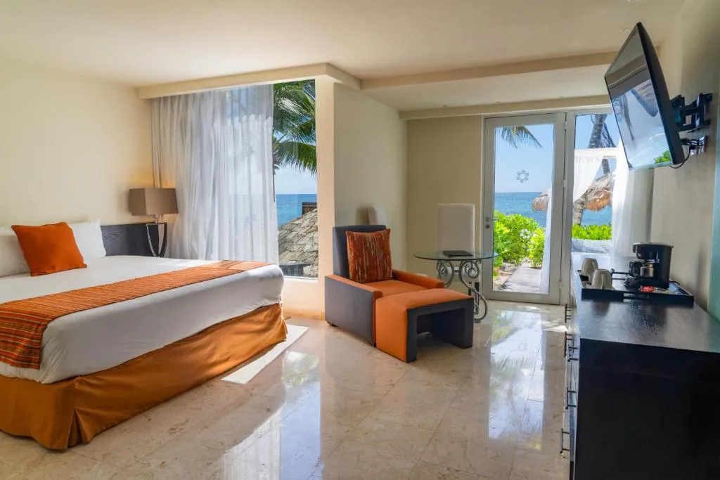 Habitación en The Sens Tulum Riviera con cama king, sala de descanso y terraza privada con vista al mar Caribe.