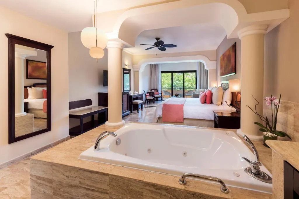 Suite en Grand Palladium White Sand Resort con cama king, jacuzzi interior y balcón con vista a la naturaleza.
